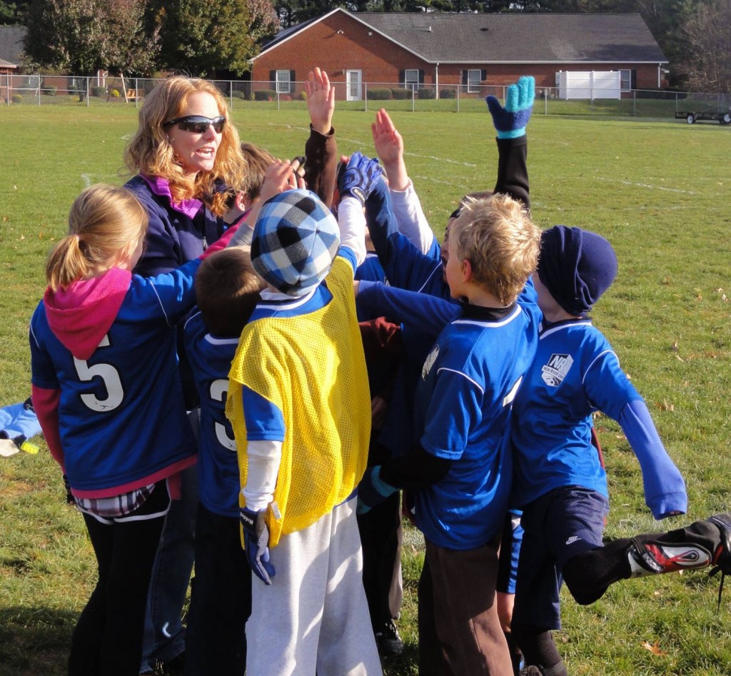 image of female coach with young players in a huddle